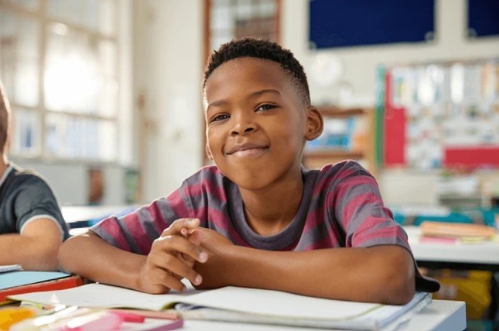 Elementary learner smiling at desk in classroom
