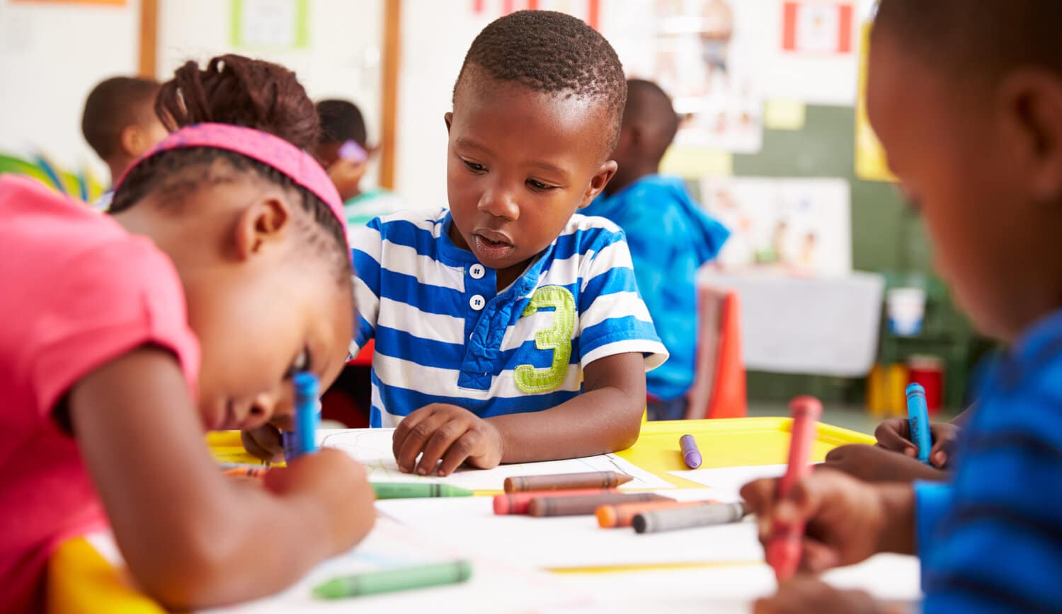 Young learner writing at a group table
